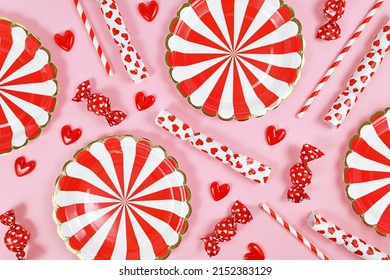 Party Flat Lay With Red Paper Plates, Heart Ornaments, Candy And Drinking Straws On Pink  Background