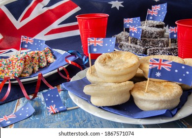 Party Food Traditionally Eaten On Australia Day With Fairy Bread,meat Pies And Lamington Cakes Against An Australian Flag Background.