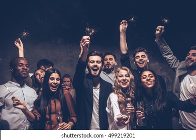 Party with friends. Group of cheerful young people carrying sparklers and champagne flutes - Shutterstock ID 499219201