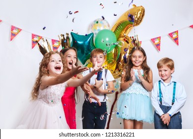 Party Fun. Group Of Beautiful Kids Throwing Colorful Confetti And Looking Happy On Birthday Party