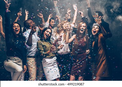 Party fun. Group of beautiful young people throwing colorful confetti and looking happy - Shutterstock ID 499219087