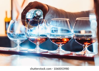 Party And Holiday Celebration Concept. Empty Glasses For Cognac On The Bar Counter. Cognac Bottling Process. With The Hand View