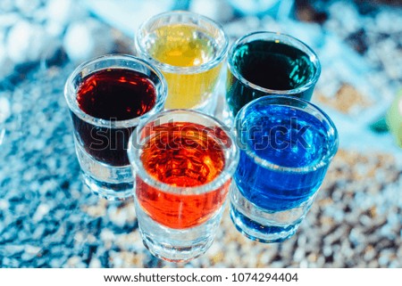 Party and holiday celebration concept. Image of multicolored liqueurs in shots on a wooden stand behind the bar. from the top view close up