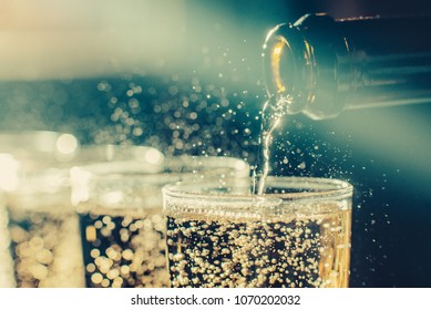 Party and holiday celebration concept. Many glasses of champagne on the table in the restaurant. Toned image. The process of bottling champagne in glasses. bubbles view with a bottle neck close