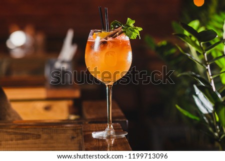 Party and holiday celebration concept. red cocktail decorated with cinnamon stick and orange in the restaurant table from the front view