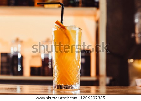 Party and holiday celebration concept. tropical cocktail or lemonade in a tall glass decorated with orange in the restaurant close