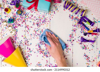 The Party Is Over. Top View Of A Person Cleaning The Table With A Cloth After A Birthday Party With A Lot Of Confetti 