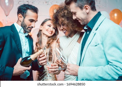 Party people in a club celebrating the new year pouring champagne in glasses