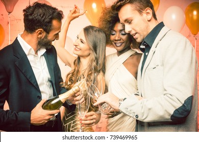 Party people in a club celebrating the new year pouring champagne in glasses