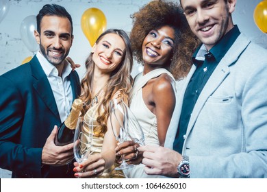 Party people with drinks celebrating new year or a birthday party together in a club