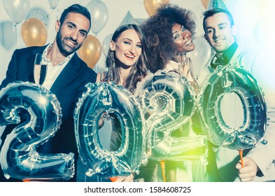 Party people women and men celebrating new years eve 2020 with sparklers and Champagne