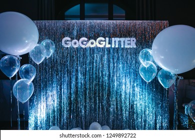 Party Photo Zone. White And Blue Balloons Hang Before Sparkling Silver Wall With Lettering 'GoGoGlitter'