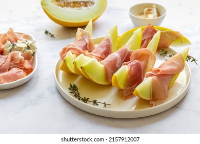 A party platter of honeydew melon and prosciutto ham. Gourmet snack, sweet-savory appetizer, seasonal food for wine. - Shutterstock ID 2157912007