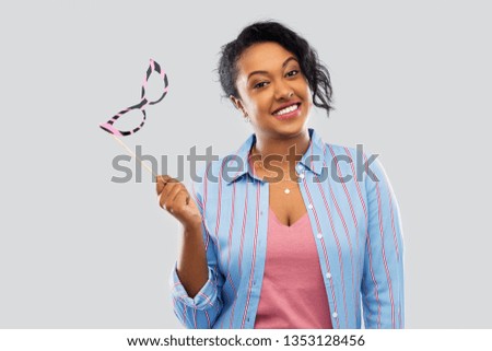 party props, photo booth and people concept - happy african american young woman with big glasses over grey background