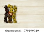 A party selection of marinated olives in a divided white ceramic tray on a rustic white wood surface