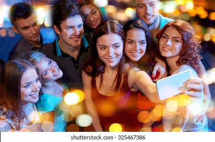 party, technology, nightlife and people concept - smiling friends with smartphone taking selfie in club - Powered by Shutterstock