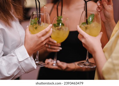 Party time concept. Cheers with glasses at pub. Toasting summer cocktails with friends. Happy young people cheering drinks at bar restaurant. Group friends partying in nightclub. Side view of hands up - Powered by Shutterstock