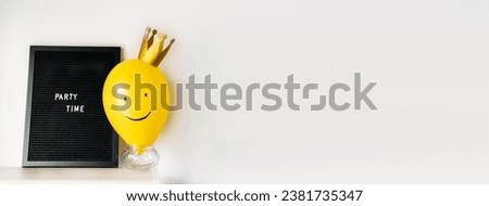 Party time fun celebration event minimal concept with smiling yellow balloon with golden crown, blackboard with text Party time and party stuff on white