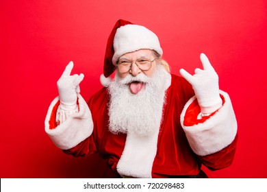 It's party time! Holly jolly swag x mas and noel!  Cool funny playful naughty grandfather with sticking tongue, comic grimace, fooling around isolated on red background, shows rock gesture