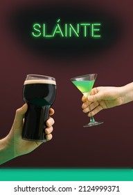 Party Toasting Modern. A Man's Hand With A Pint Of Black Stout Beer Glass And A Girl's Hand Holds A Martini Glass With Green Cocktail. Irish Gaelic Slainte Or Cheers In English Green Neon Light