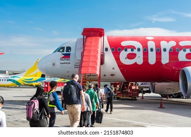 Pasay, Metro Manila, Philippines - April 2022: Passengers walk through the tarmac to board an Air Asia Airbus domestic plane.
