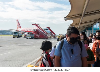 Pasay, Metro Manila, Philippines - April 2022: Passengers walk through the tarmac to board an Air Asia domestic plane.