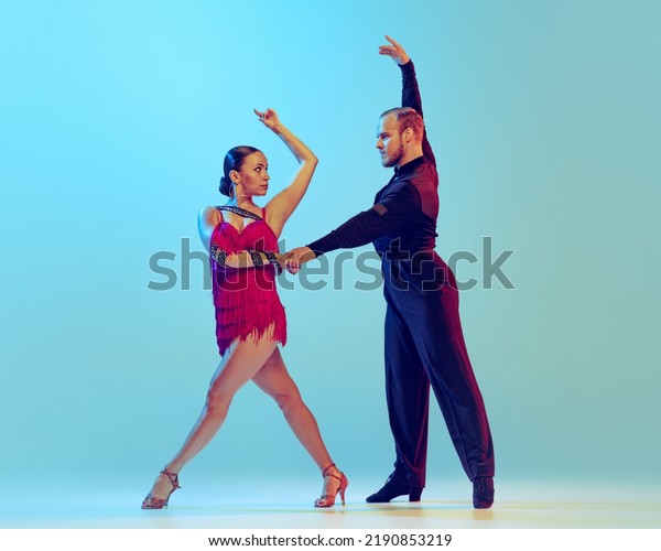 Paso doble. Studio shot of young couple,\
professional dancers dancing ballroom dance isolated on blue\
background. Concept of art, dance, beauty, music, style. Copy space\
for ad. International\
Dance