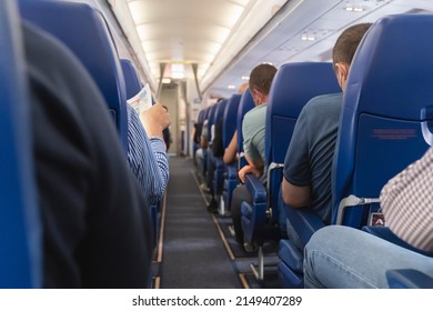 Passage in the plane.Economy class interior, aircraft cabin. Passengers sit in their seats.Family enjoying trip in aircraft. Transportation safety. 