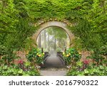 Passage to the summer sunny park through the arch with flowers