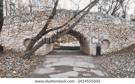 passage through a brick tunnel in an ancient stone bridge in a city park in autumn