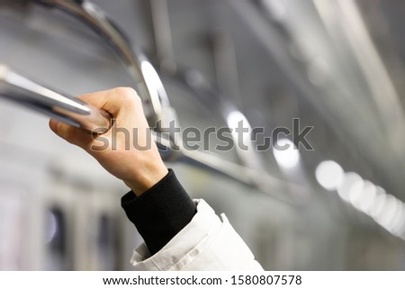 Passanger holding  handrail in subway train, soft focus on hand. Handrail in transport - a source of germs and infections. 