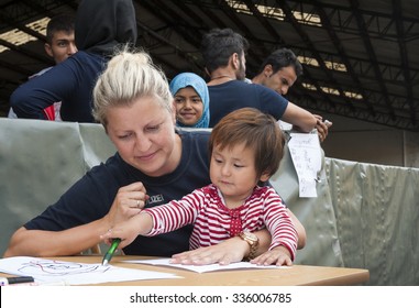 Passau, Germany - August 1, 2015: A german police officer takes care of a little refugee child in the registration area of Passau. 