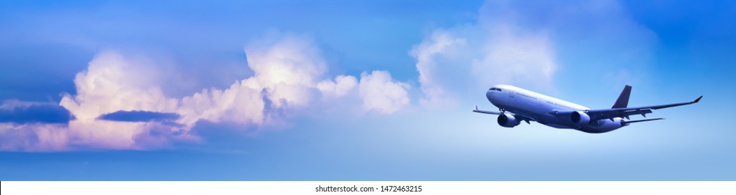 Passenger aircraft at blue cloudy sky background at sunrise, panoramic view. Wide landscape with an airplane for your banner concept for travel, an airline agency or international air transportation.