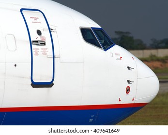 Passenger Aircraft Nose Section And Exit Door Close Up With Emergency Exit Markings In Russian