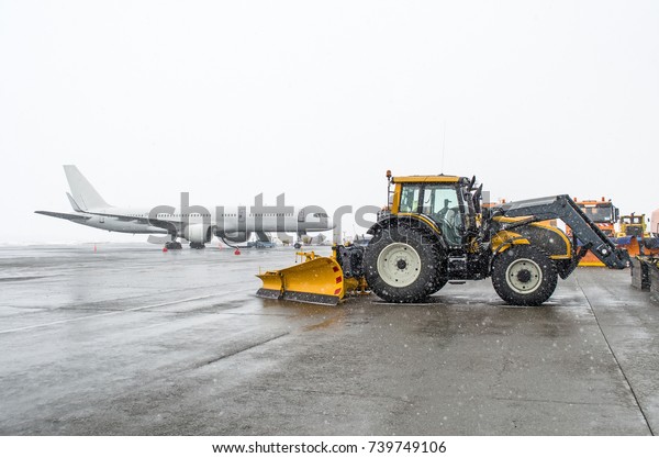 Passenger aircraft in the parking lot and a snow\
tractor in snowy weather in\
winter
