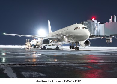 Das Passagierflugzeug steht an der Bordbrücke am Nachtflughafen. Der Gepäckraum des Flugzeugs ist offen und das Gepäck wird geladen