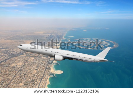 Passenger airliner flying over Dubai city and sea coastline
