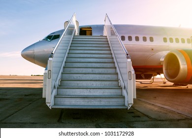 Passenger airplane with a boarding steps in the morning sun
