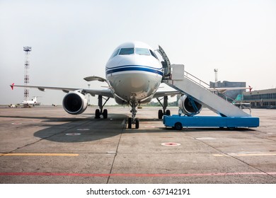 Passenger airplane with open luggage compartment and boarding ramp near at the airport apron
