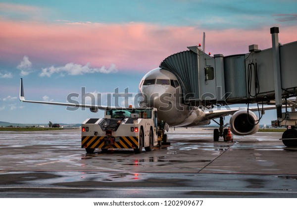 Passenger airplane and tow truck at the jet bridge.\
Front view