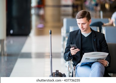 Passenger in an airport lounge waiting for flight aircraft. Young man with cellphone in airport waiting for landing