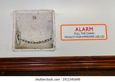 Passenger alarm chain inside an old fashioned railway carriage, and sign warning about improper use