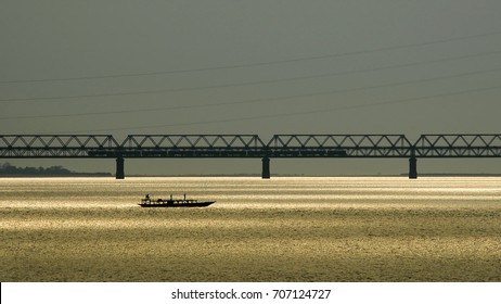 Passenger Boat Crossing Brahmaputra River At Sunset Over Saraighat Road-cum-rail Bridge, Guwahati, India.