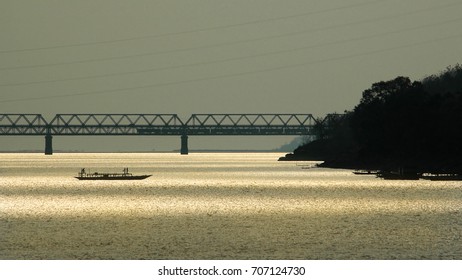 Passenger Boat Crossing Brahmaputra River At Sunset Over Saraighat Road-cum-rail Bridge, Guwahati, India.