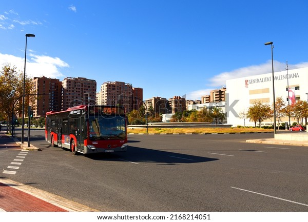 Passenger bus on road. Red city bus travels down\
street in city. Public transport and city buses in Eurupe. Сity\
street, road traffic, cars on road, people and buildings. Dec 09,\
2021, Spain, Valencia