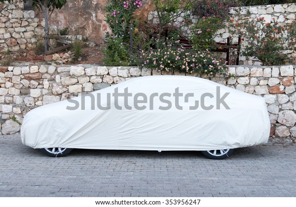 Passenger\
car covered with white sheet on the\
pavement