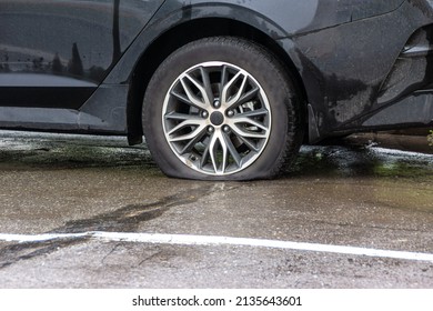 A Passenger Car With A Flat Tire Stands On The Pavement, Wet From The Rain, Waiting For A Service Car Or Auto Repairman, Selective Focus