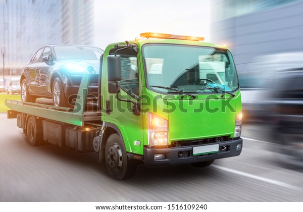 Passenger car\
loaded onto a tow truck for transportation, delivered to the\
destination. With motion blur speed\
effect