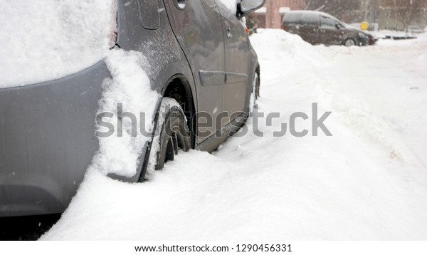 Passenger\
car stuck in snow, side view. Car blocked in the yard by snowdrift\
after heavy blizzard. Bad weather\
conditions.