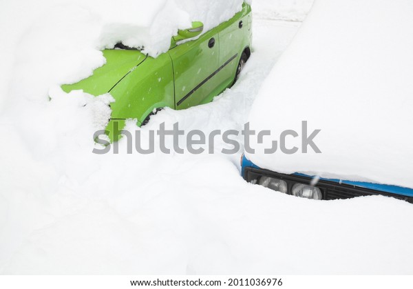 Passenger cars\
in the snowdrift (snow bank) on the parking lot. Cars covered with\
snow after the snowstorm in winter.\
